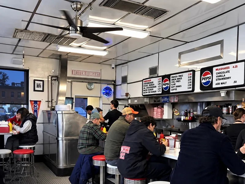 6:00 PM. Diners along the chrome counter under the menu boards in the early evening.